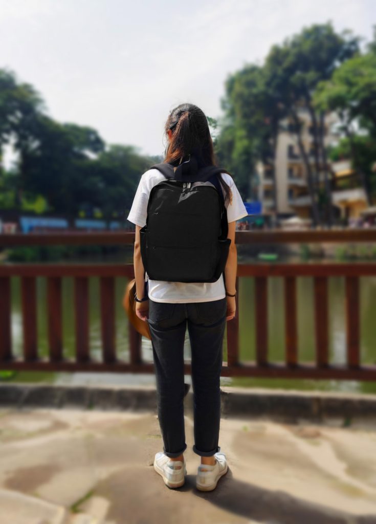 a woman with a backpack standing on a bridge
